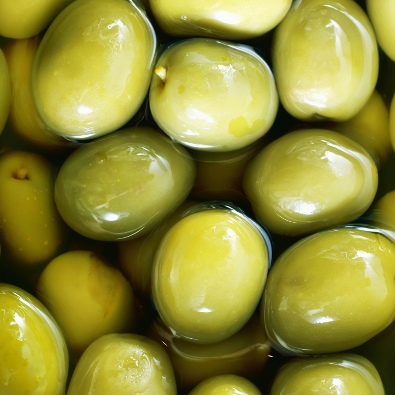 An overhead zoomed in photo of a cluster of olives in a bowl filled with an appetizing marinade.
