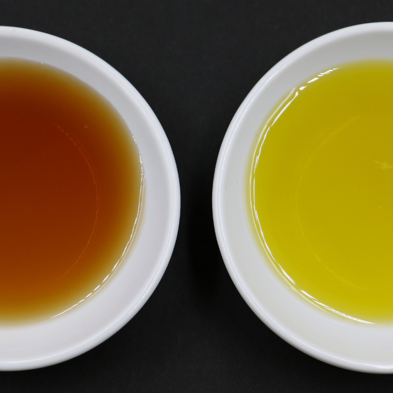 An overhead image of two bowls -- one containing extra virgin olive oil and the other containing vinegar.