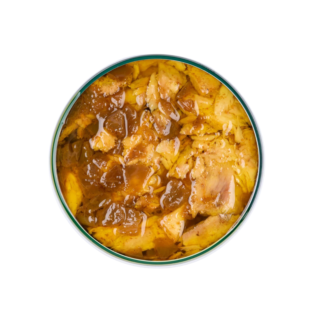 Inside the tin, generous flakes of yellowfin tuna belly glisten under a vibrant, golden curry sauce. Translucent bits of onion mingle with the fish, creating a rich, glossy layer that hints at warmth and spice. The hearty texture and bold color promise a flavorful, aromatic bite.