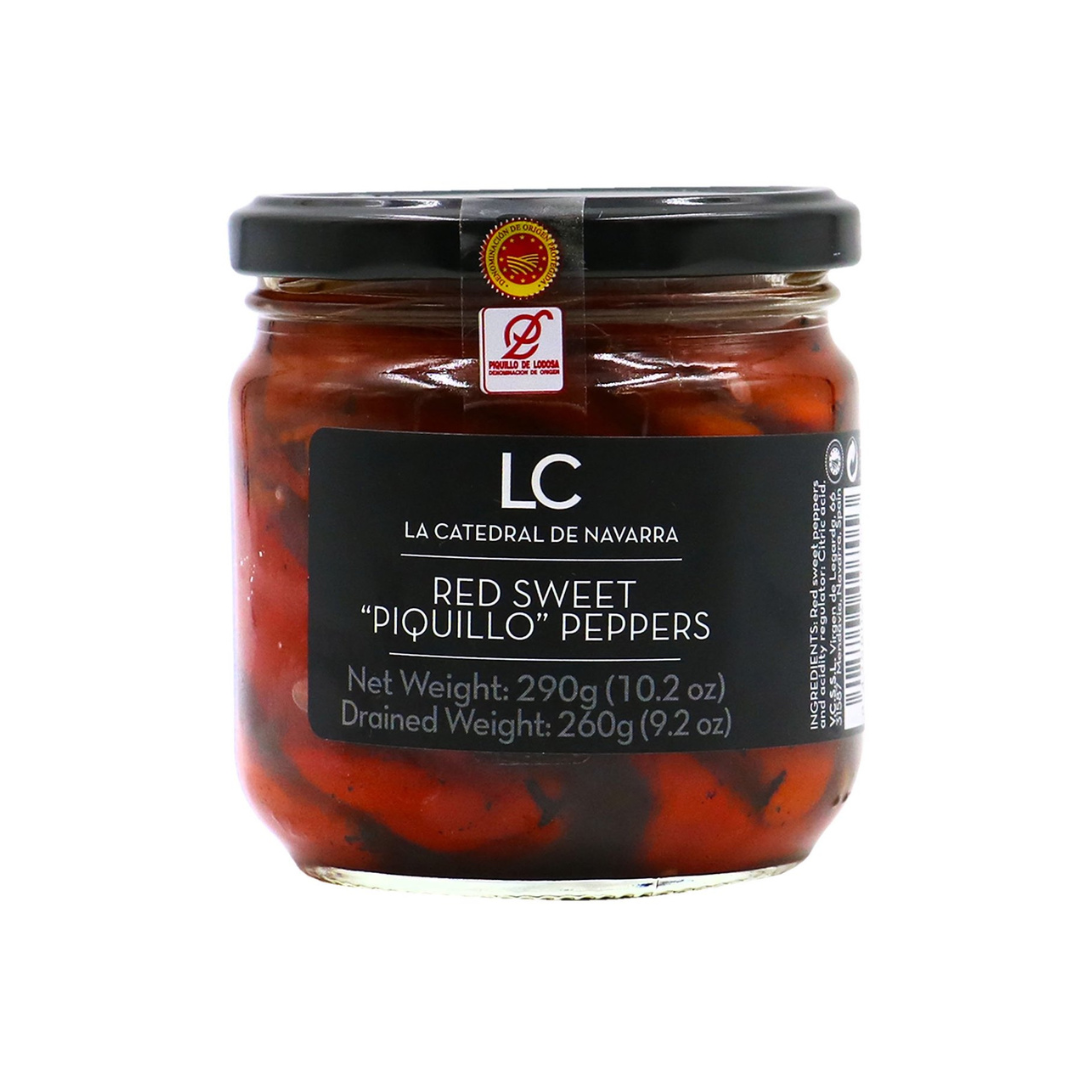A jar of La Catedral de Navarra Red Sweet Piquillo Peppers showcases vibrant roasted peppers through clear glass. The black label highlights its premium Spanish origin and DOP certification, signaling authenticity and gourmet quality for Mediterranean cuisine.