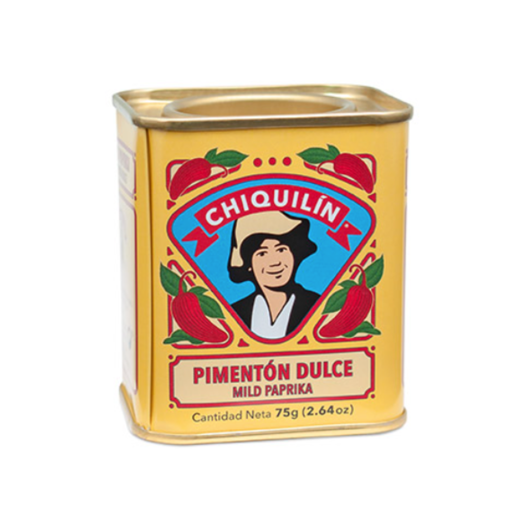 A yellow metal tin of Chiquilín Pimentón Dulce (Mild Paprika), featuring a colorful label with a smiling woman in traditional attire at the center. Surrounding her are red chili peppers and green leaves. The label also includes the product name in Spanish and English, with the net weight indicated as 75g (2.64 oz). The tin has a gold-colored lid and a rectangular shape.