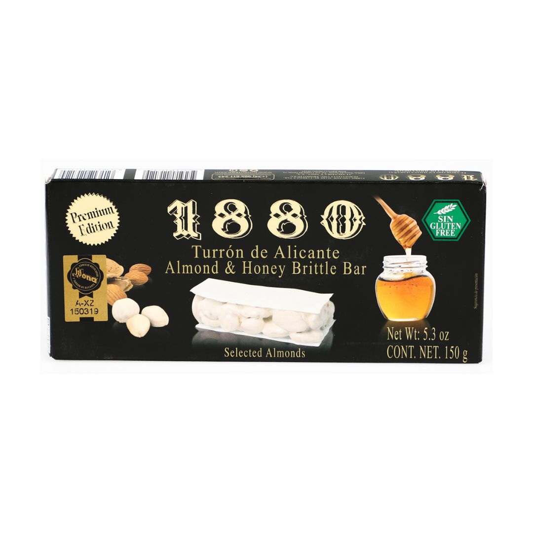A box of 1880 Turrón de Alicante showcases Spain’s classic almond and honey brittle bar. The packaging features whole almonds, a jar of honey, and a premium label, emphasizing its gluten-free, artisanal quality. A traditional Spanish holiday treat made with selected almonds.