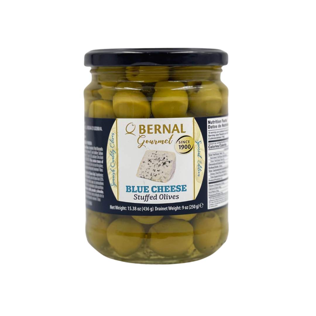 A jar of Bernal Gourmet Blue Cheese Stuffed Olives, showcasing plump green Spanish olives filled with creamy blue cheese. The elegant label features a wedge of blue cheese and premium branding, highlighting this savory snack as a gourmet tapas essential.