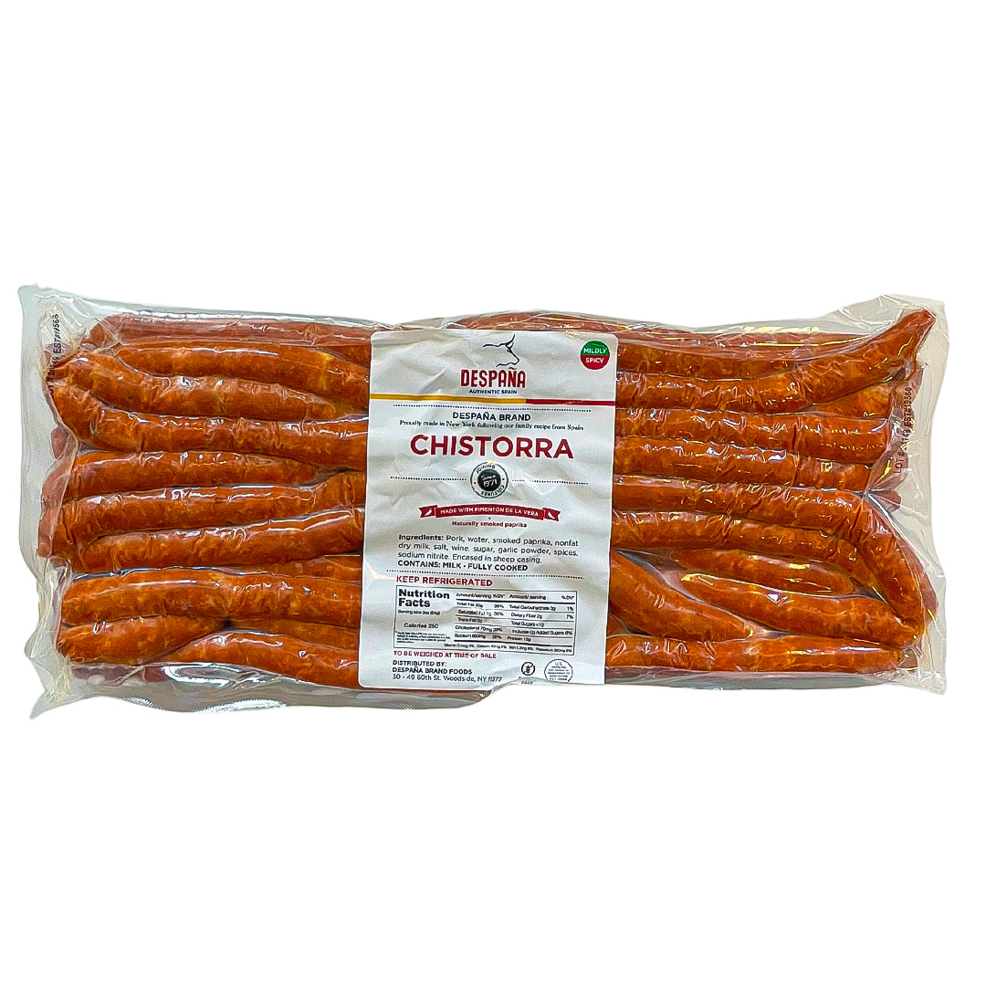 A large vacuum-sealed pack of Despaña Chistorra with a white label at center. Labeled “Mildly Spicy,” gluten-free, and made with Pimentón de la Vera. A generous batch of fully cooked Spanish sausages, ready to serve or sizzle.
