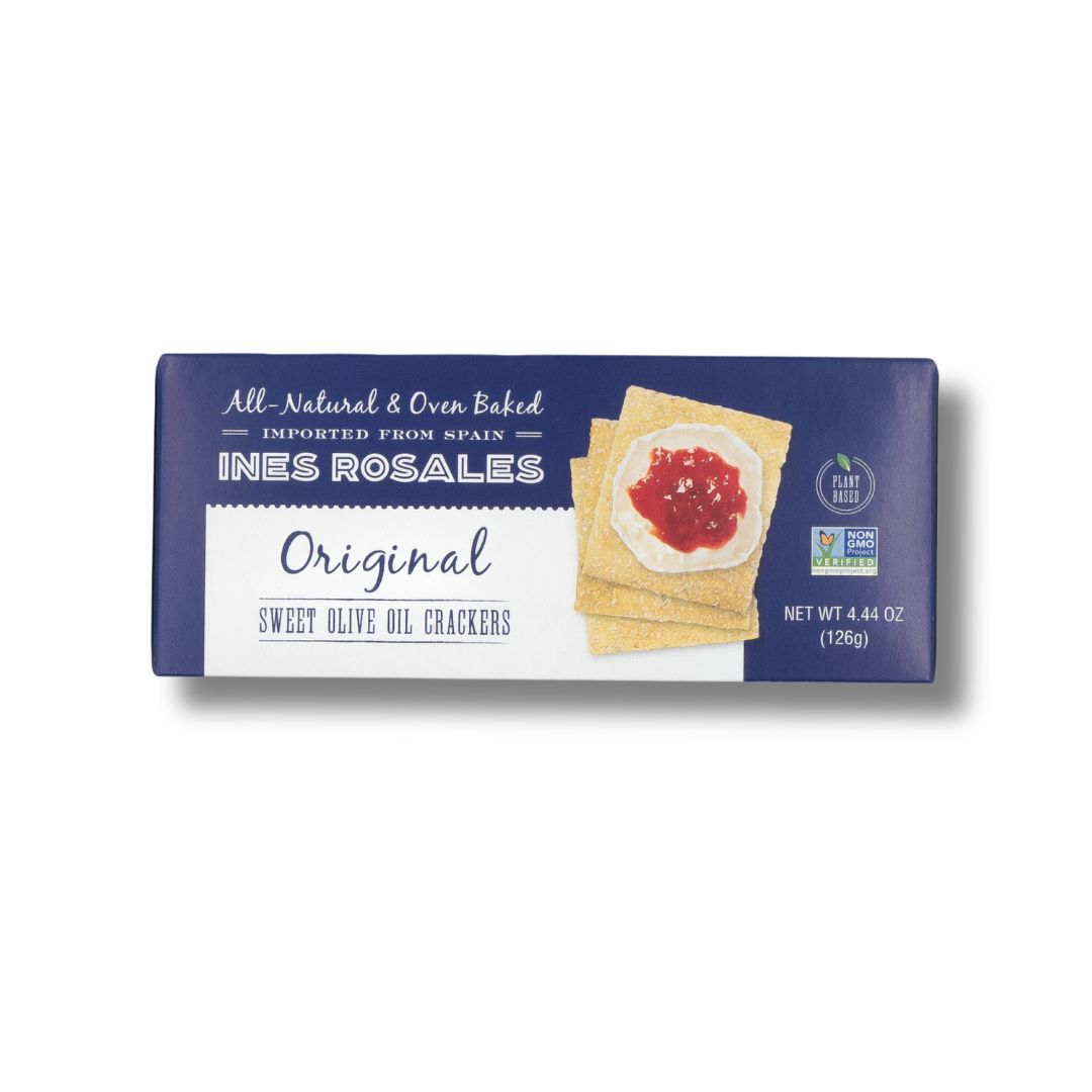 A rectangular box of Ines Rosales Original Sweet Olive Oil Crackers. The packaging is dark blue and white with an image of square crackers topped with creamy cheese and red jam. The product is labeled as all-natural, oven-baked, imported from Spain, plant-based, and non-GMO. Net weight is 4.44 oz (126g).