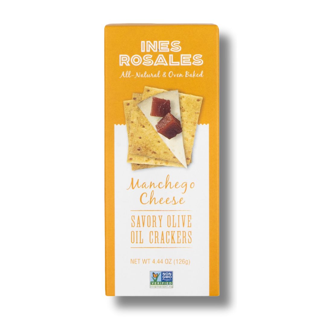 A bright orange box of INES ROSALES Manchego Cheese Savory Olive Oil Crackers. The front label features a stack of crackers topped with a slice of Manchego cheese and quince paste. Text on the box highlights that the product is all-natural, oven-baked, and Non-GMO Project Verified. The net weight is 4.44 oz (126g).