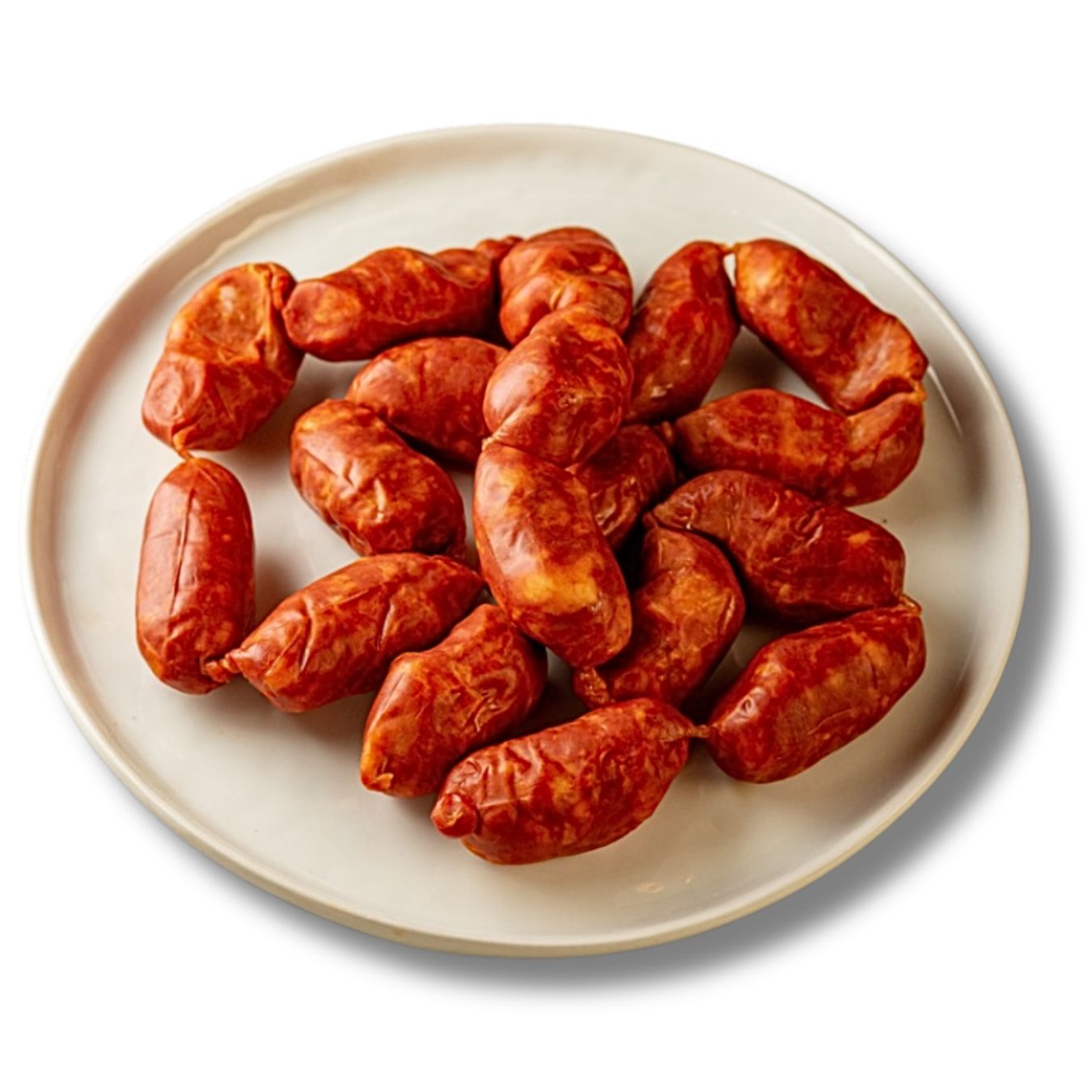 A plate of mini Spanish chorizo sausages arranged on a white ceramic dish. Their plump, rustic shape and deep red hue highlight the paprika-rich blend. Perfect for tapas or bite-sized appetizers. Authentic, mildly spicy Spanish flavor.