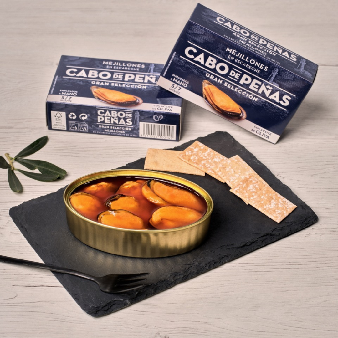 A board that is composed of an open tin of cabo de peñas mussels alongside breadstick garnishes.