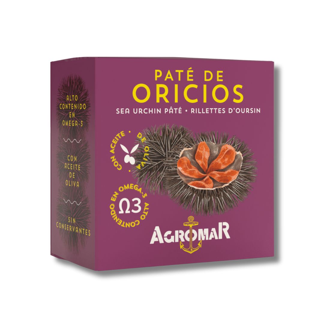 A purple box of Agromar Paté de Oricios (Sea Urchin Pâté). The front of the packaging features a detailed illustration of an open sea urchin showing its orange roe. Text on the box includes product names in Spanish, English, and French: "Paté de Oricios," "Sea Urchin Pâté," and "Rillettes d’Oursin." Other labels on the packaging highlight features like “Con Aceite de Oliva” (With Olive Oil), “Alto Contenido en Omega-3” (High Omega-3 Content), and “Sin Conservantes” (No Preservatives).