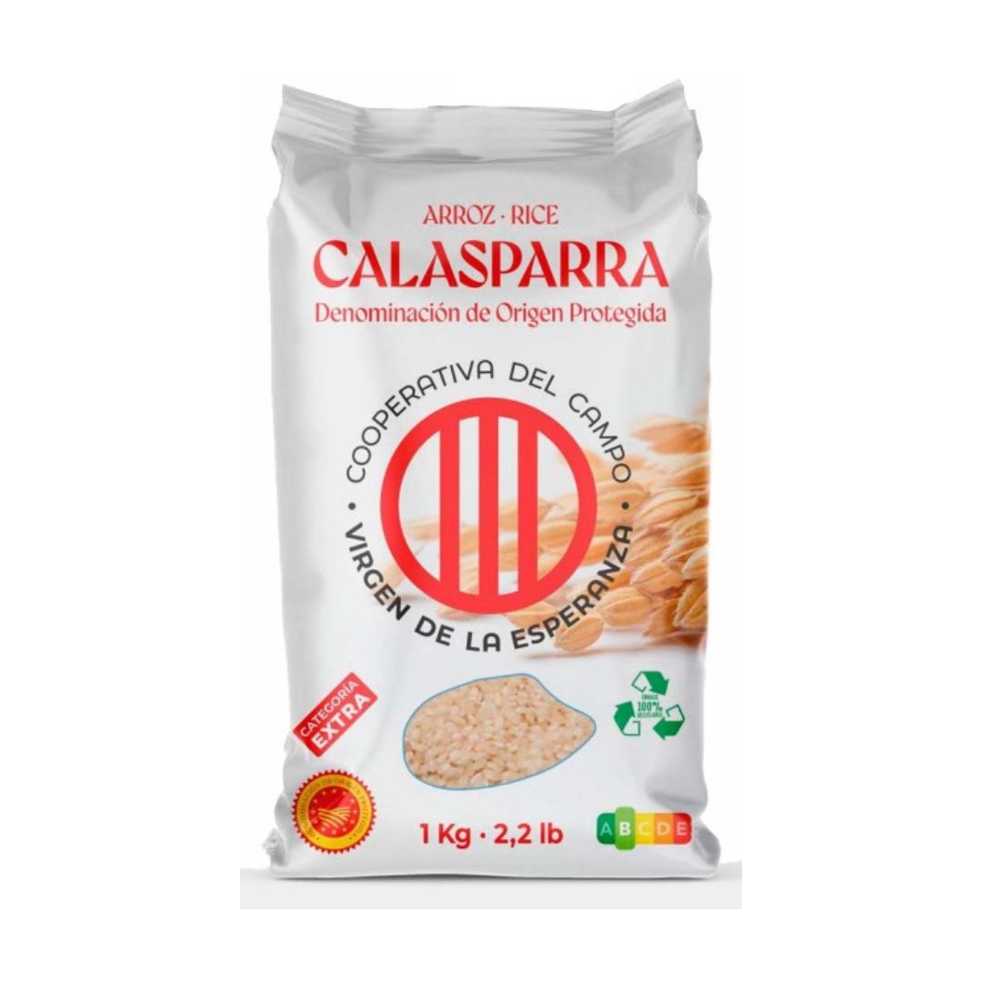 A 1 kg (2.2 lb) bag of Calasparra rice labeled with "Denominación de Origen Protegida." The packaging is white with red and black text and features the logo of "Cooperativa del Campo Virgen de la Esperanza." There is an image of rice grains and stalks, a red quality seal marked “Categoría Extra,” and icons indicating 100% recyclable packaging and nutritional information.