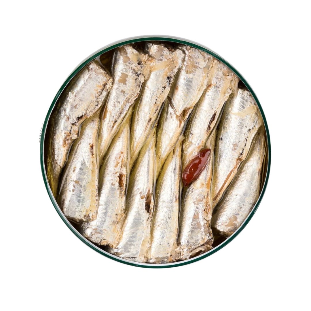 A top-down view of a gourmet tin of La Curiosa sardines in olive oil. One sardine stands out with a red chili, indicating a spicy twist.