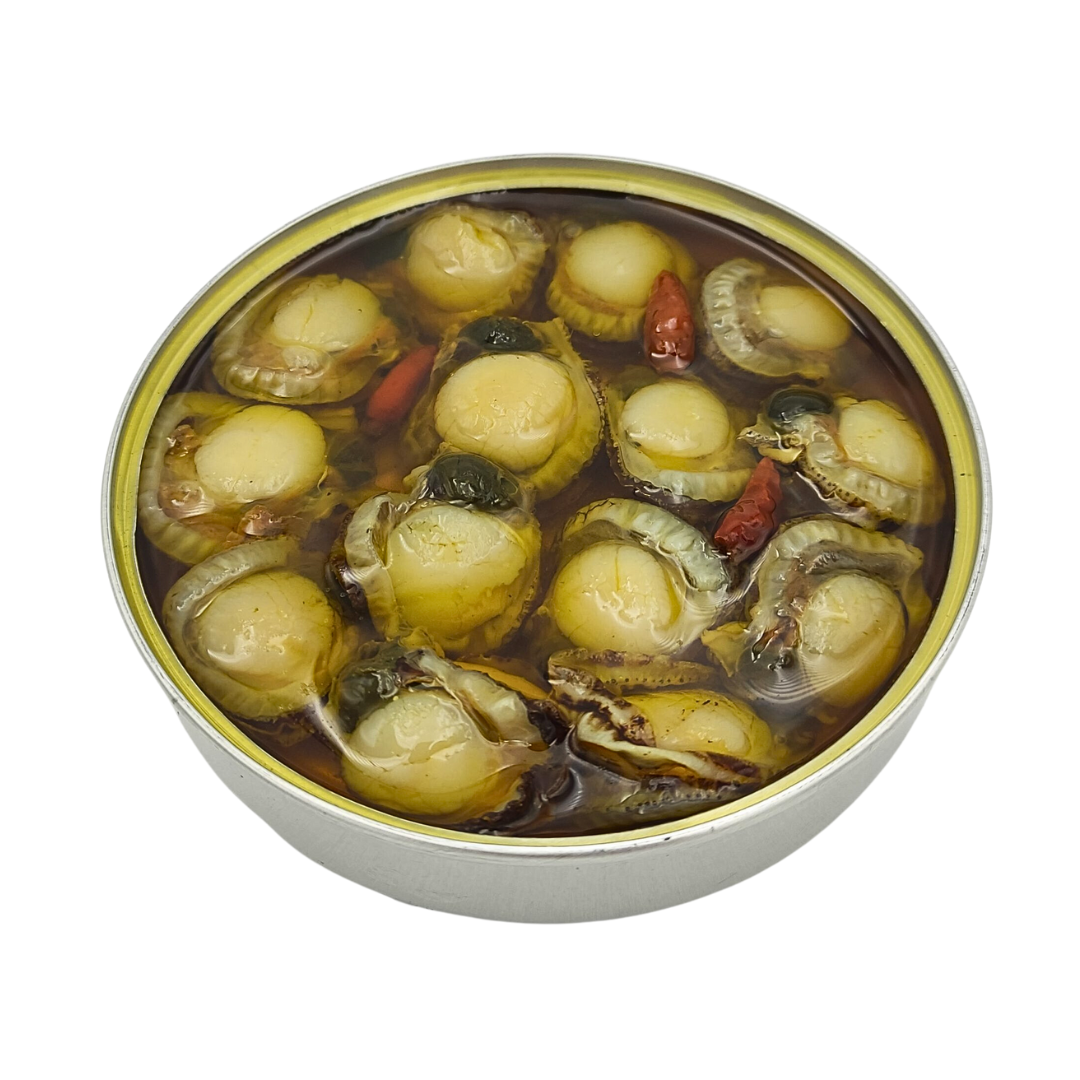 Close-up of an open tin of Galician scallops in olive oil with garlic and chili. The tender zamburiñas are nestled in golden oil with whole red chilies, highlighting their premium Spanish origin and artisanal preservation.