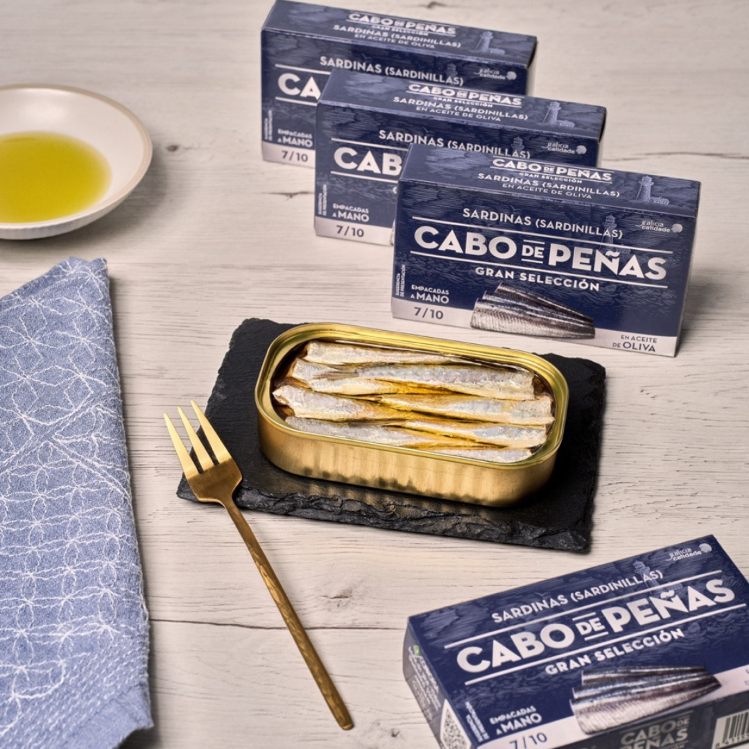 A serving plate with a tin of open small sardines in olive oil by cabo de peñas.