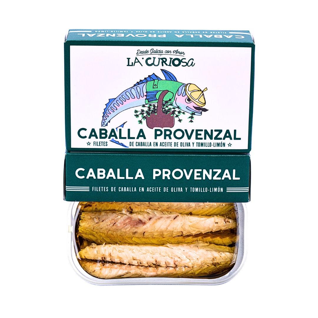 Open tin of La Curiosa Caballa Provenzal shows tender mackerel fillets in olive oil with lemon thyme. The bright, illustrated packaging evokes Galician artistry and emphasizes the gourmet, Mediterranean flavor profile.