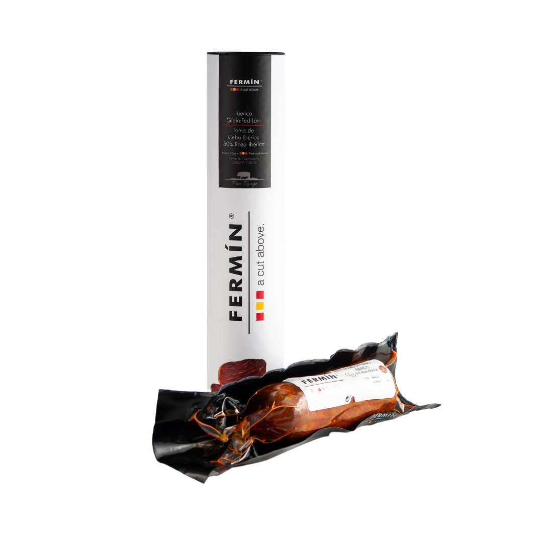 A log of lomo serrano presented in a vacuum sealed casing, alongside a branded Fermin tube that it is presented in.