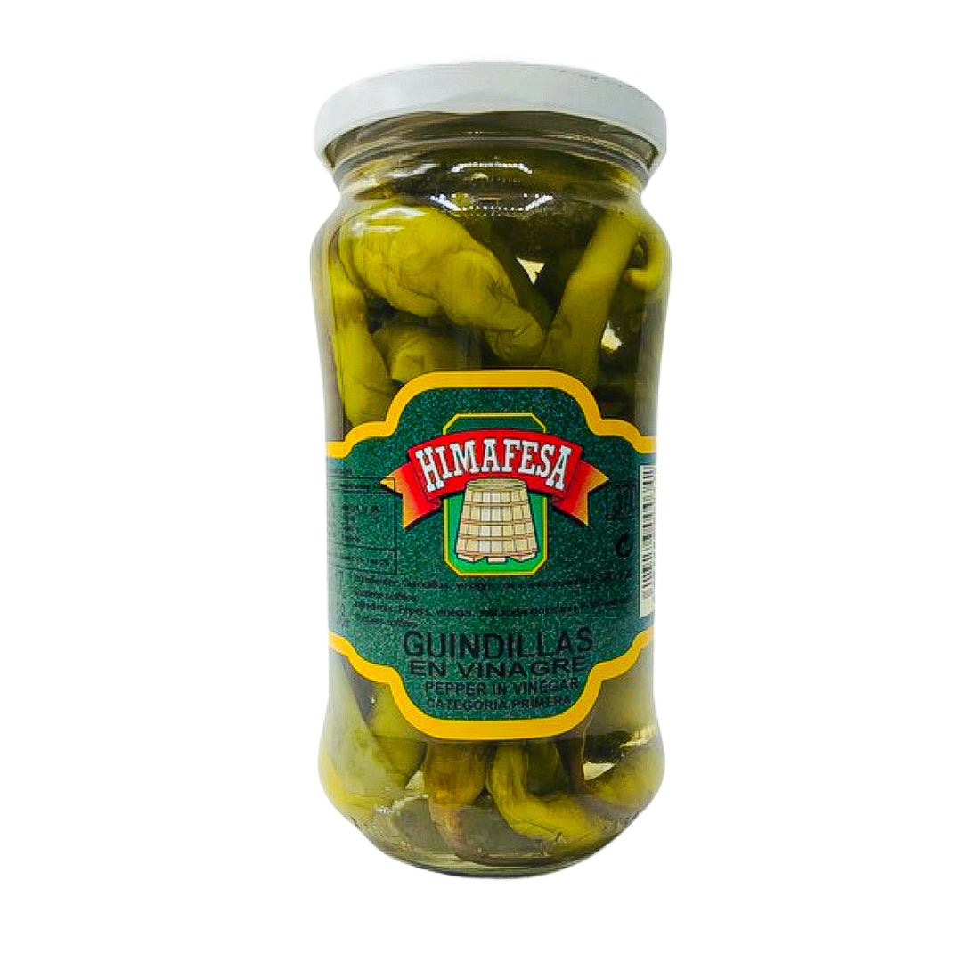 A clear jar of Himafesa guindilla peppers preserved in vinegar, showcasing premium whole green chili peppers. These Spanish-style pickled peppers add a tangy, mildly spicy kick to tapas, charcuterie boards, and Mediterranean recipes.