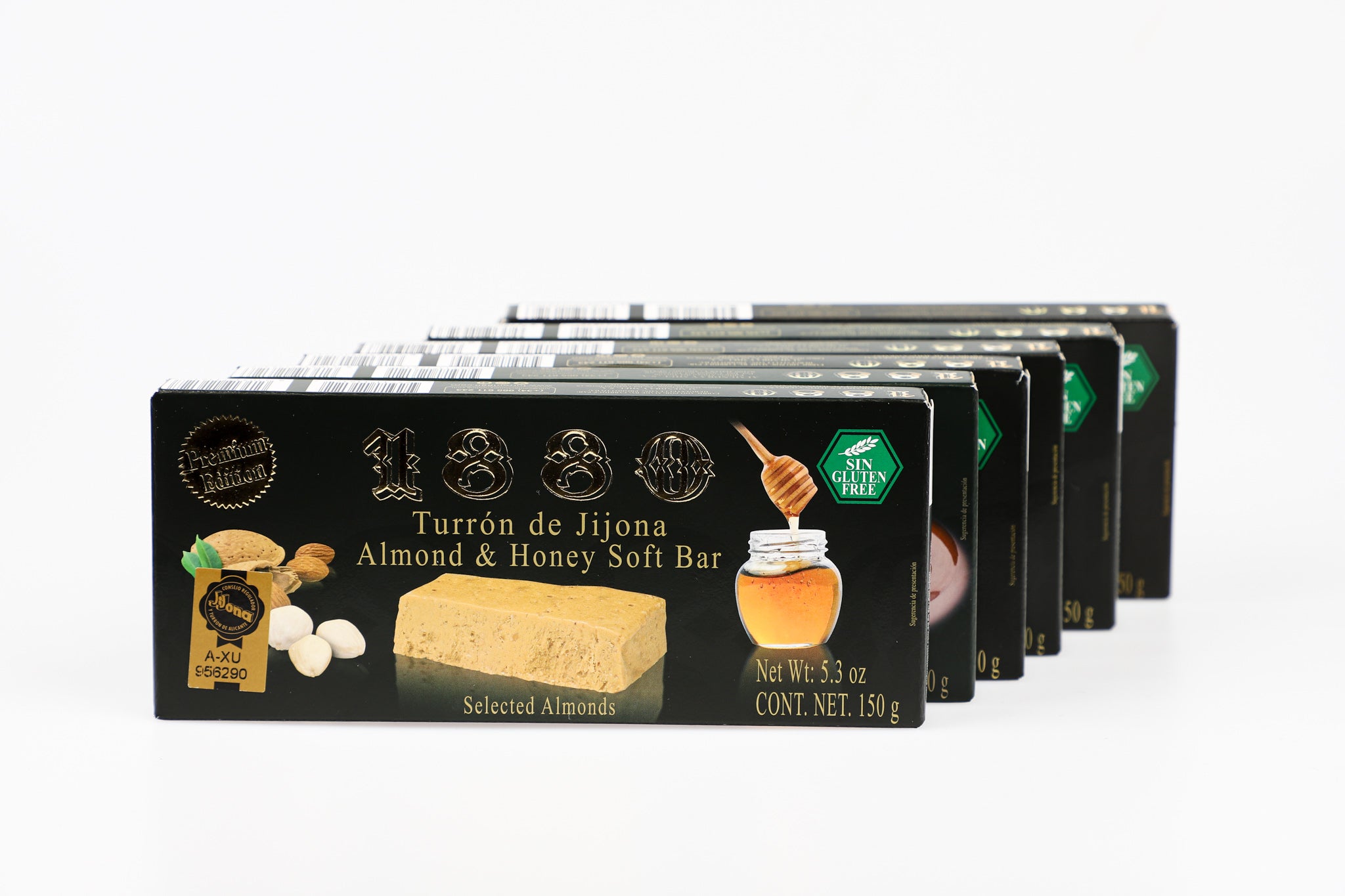 A row of sleek black boxes of 1880 Turrón de Jijona—Almond & Honey Soft Bar—is neatly stacked, showcasing the product’s premium appeal. The glossy packaging highlights the rich turrón block, golden honey jar, and scattered almonds, signaling its indulgent, gluten-free quality and artisanal Spanish roots.