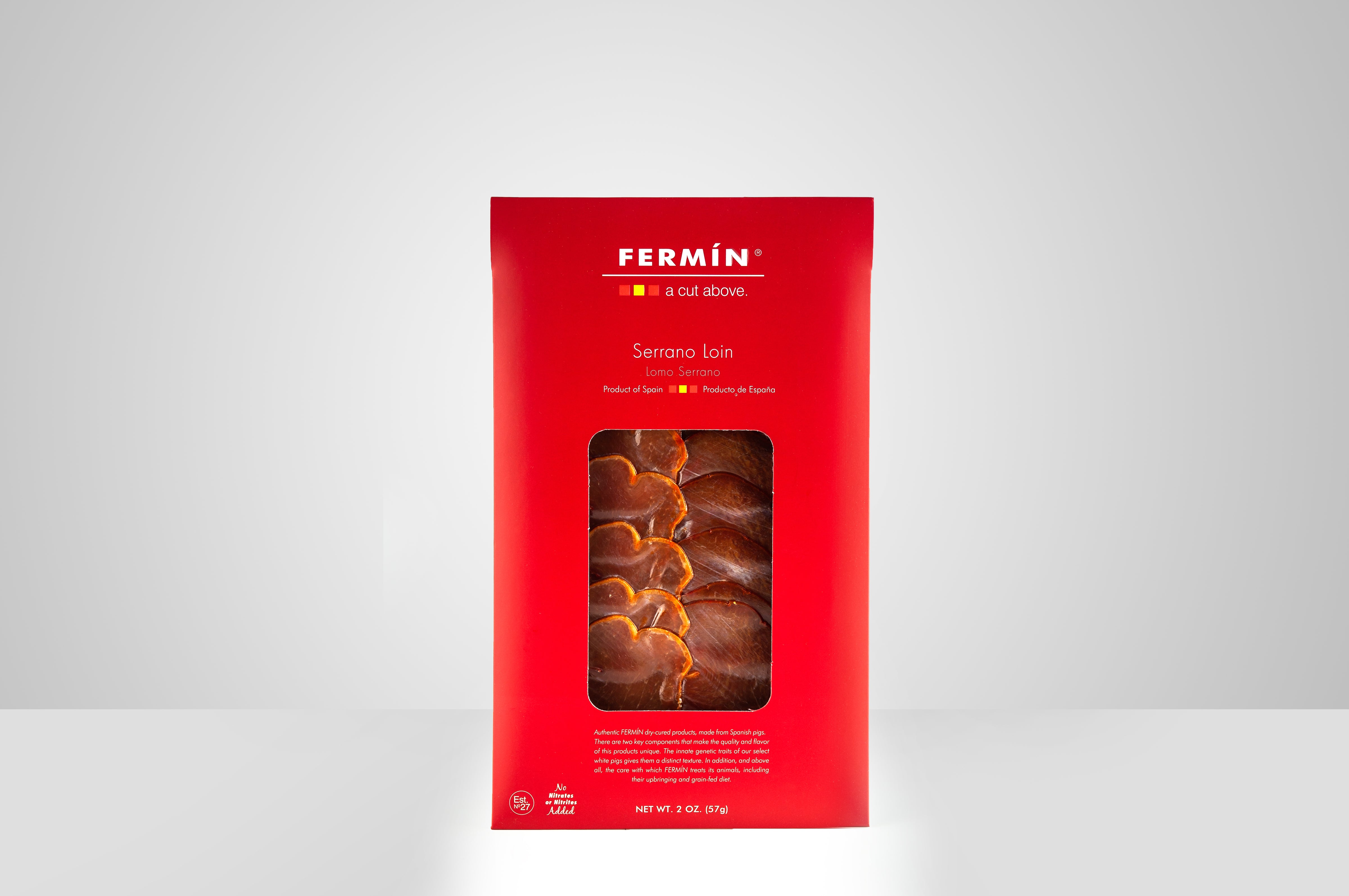 A sleek red package of Fermín Serrano Loin showcases delicately marbled slices through a central window. With minimalist design and premium Spanish origin, it captures the elegance of artisanal cured meats.