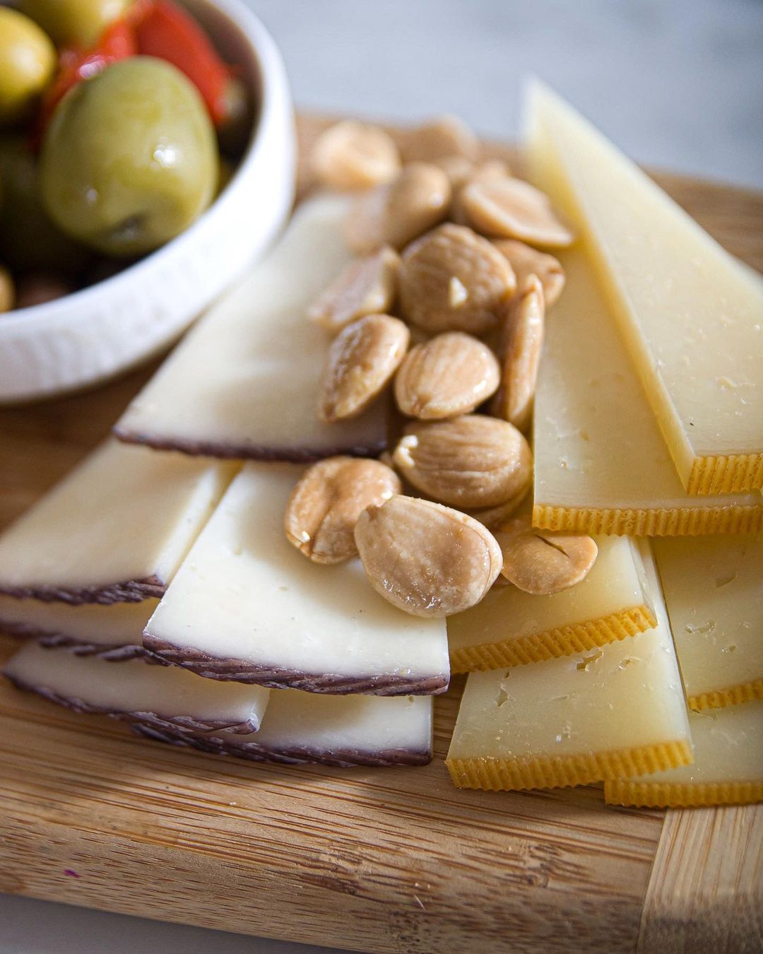 Marcona almonds served with Manchego cheese and olives on a wooden board. Classic Spanish appetizer setup for tapas and wine pairings.