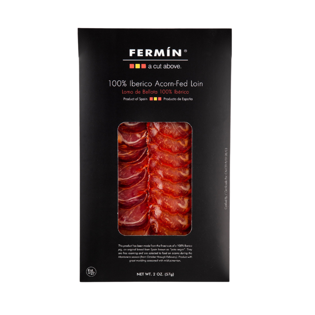 A bold black package of Fermín 100% Ibérico Acorn-Fed Loin reveals a line of ruby-red, marbled slices through its window. This sleek design spotlights the rich, nutty flavor of premium Spanish lomo de bellota.