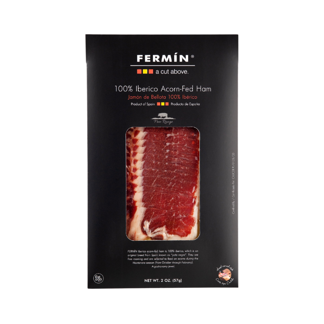 A 2 oz pack of Fermín 100% Ibérico Acorn-Fed Ham, elegantly boxed in black with a clear window showcasing the marbled slices. Labeled free-range and product of Spain—premium Jamón de Bellota at its finest.