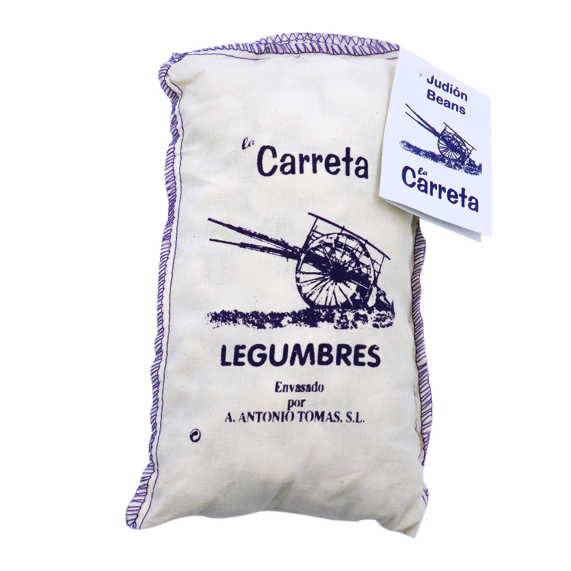 A cloth bag of La Carreta Judión Beans (large white beans) labeled "Legumbres" is shown, packaged by A. Antonio Tomas, S.L. The design features a rustic illustration of a traditional cart and is trimmed with a purple stitched border. A tag attached to the bag reads "Judión Beans" and replicates the same cart image and branding.