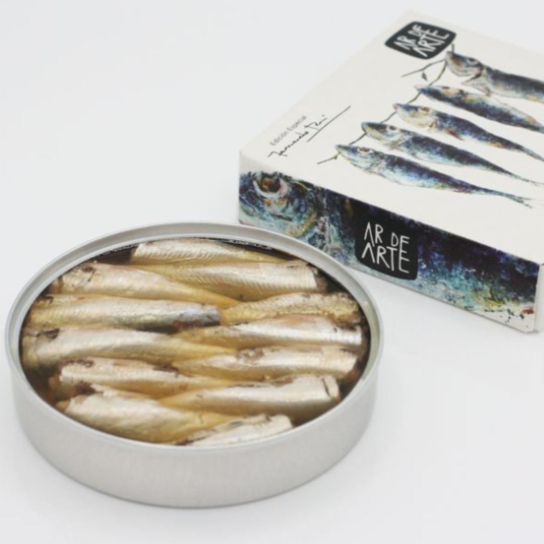 Open tin image of small sardines in olive oil next to their packaging.