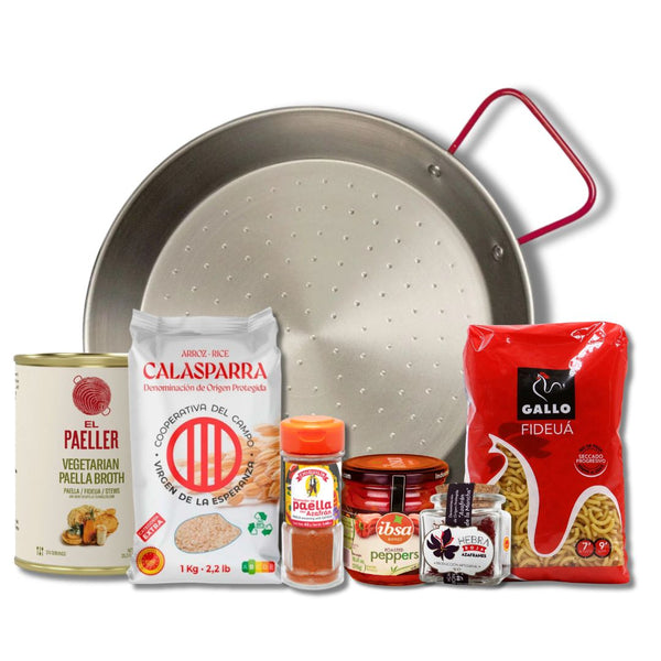 A cooking set featuring a stainless steel paella pan with a red handle, surrounded by various ingredients including a can of El Paeller vegetarian broth, Calasparra rice, Calasparra garlic, Calasparra pepper, and a bag of Gallo Rdeuia pasta, all arranged on a white background.
