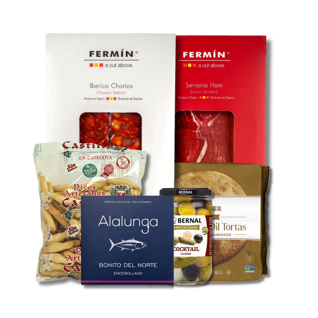 A gift hamper assortment of Spanish food products, including Fermin Iberico Chorizo and Serrania Ham, Castalia Patatas, Alalunga Bonito del Norte encollado, and Bernal Cocktail Olives, arranged together on a white background.