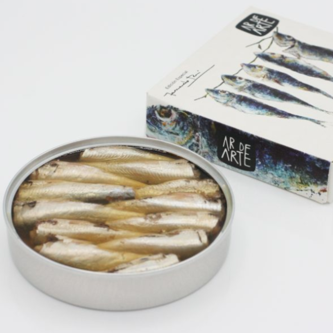 Open tin image of small sardines in olive oil next to their packaging. 